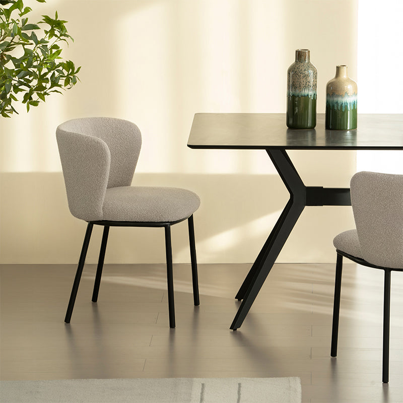 Chaise design Karin en tissu bouclé beige, avec dossier large et pieds en métal noir. Parfaite pour salle à manger, cuisine ou bureau. Collection OFCASA.