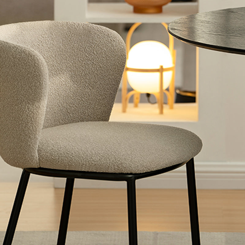 Chaise design Karin en tissu bouclé beige, avec dossier large et pieds en métal noir. Parfaite pour salle à manger, cuisine ou bureau. Collection OFCASA.