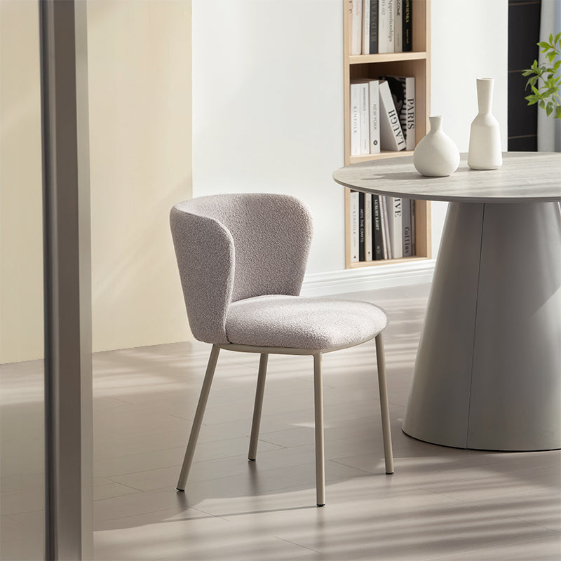 Chaise design Karin en tissu bouclé beige, avec dossier large et pieds en métal noir. Parfaite pour salle à manger, cuisine ou bureau. Collection OFCASA.